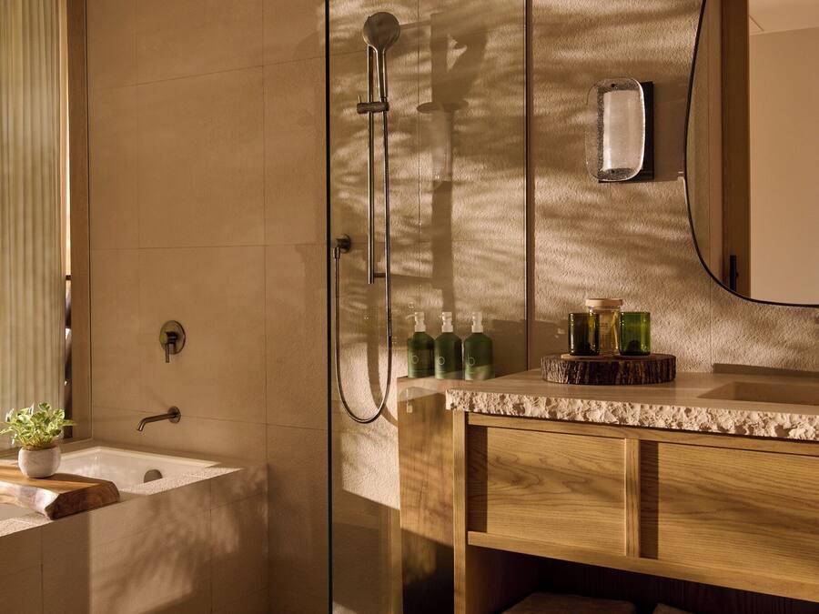 Un baño moderno con cabina de ducha de vidrio, tocador de madera y un espejo grande.