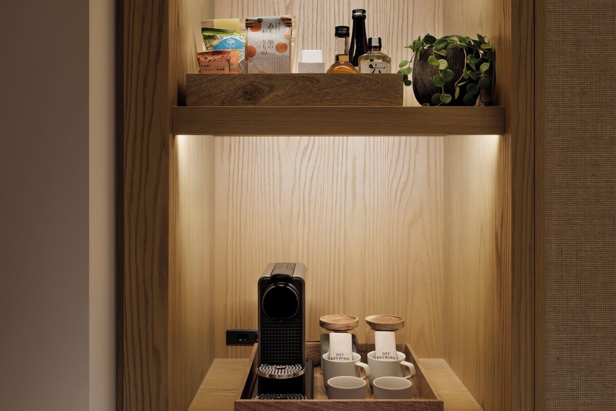 A wooden shelf unit with a coffee maker, cups, and a tray.