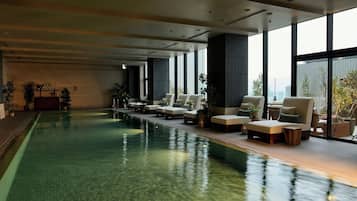 Zona de piscina con sillones de descanso y plantas en macetas.