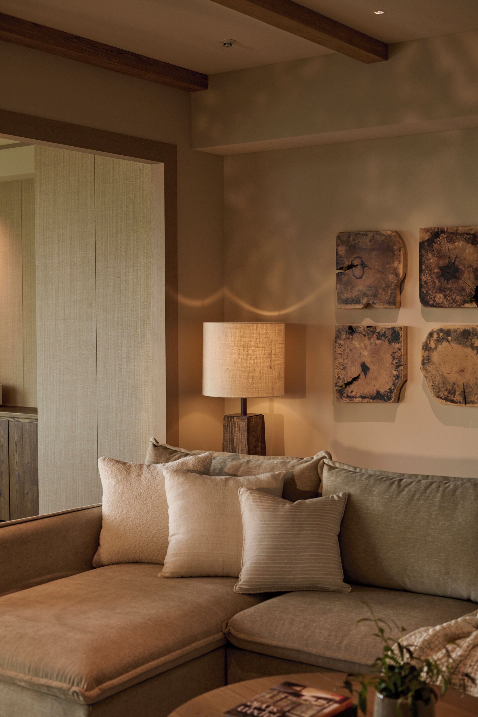 A cozy corner with a sectional sofa, a lamp, and rustic wall art.