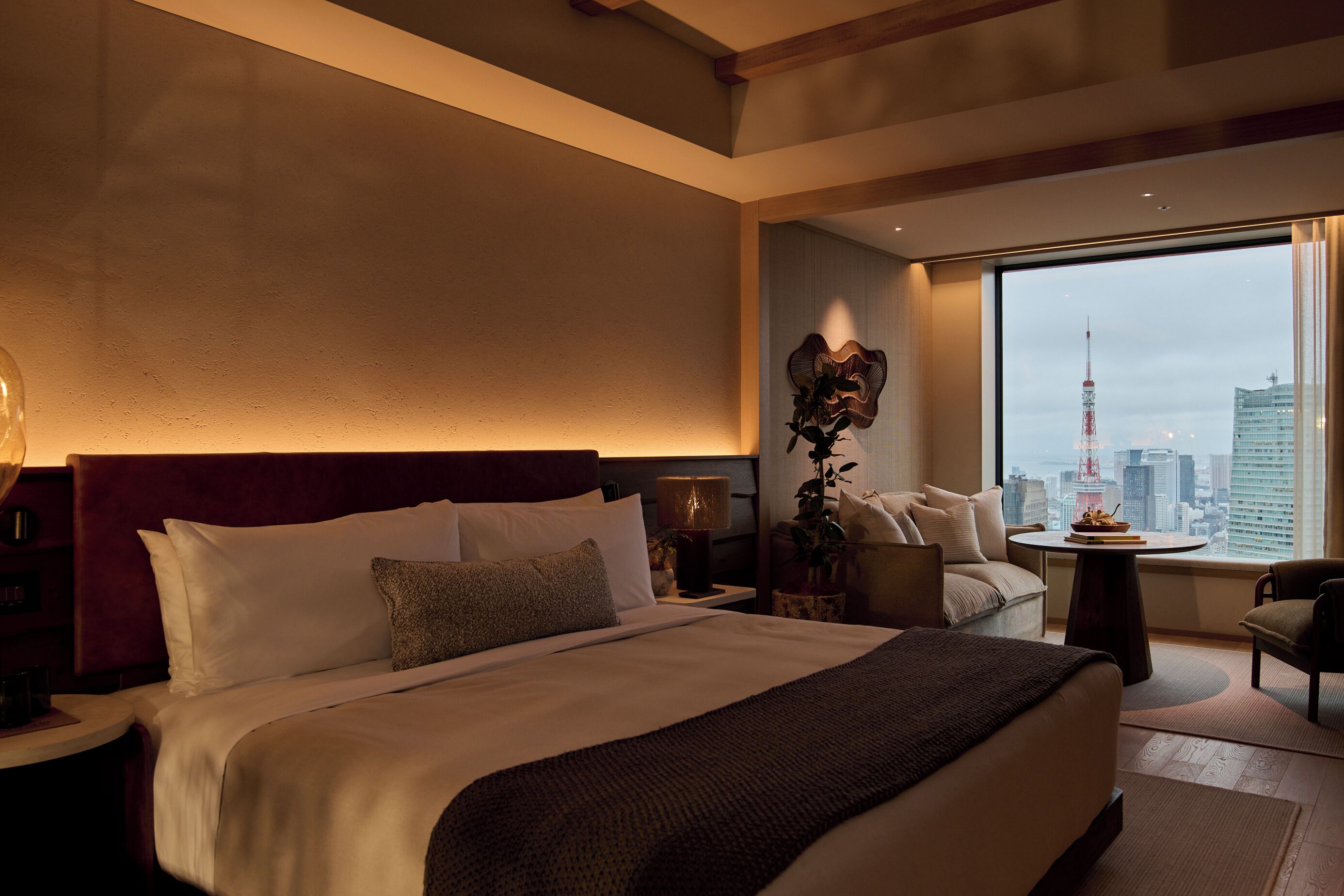 A hotel room with a large bed, a view of the cityscape, and a city tower.
