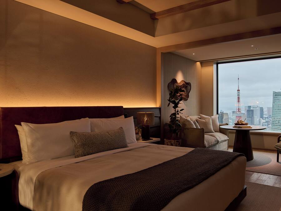 A hotel room with a large bed, a view of the cityscape, and a city tower.