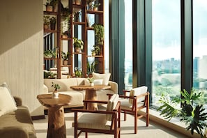 A modern living room with a sofa, chairs, a coffee table, and a bookshelf filled with plants. - 1 Hotel Tokyo (Tokyo)
