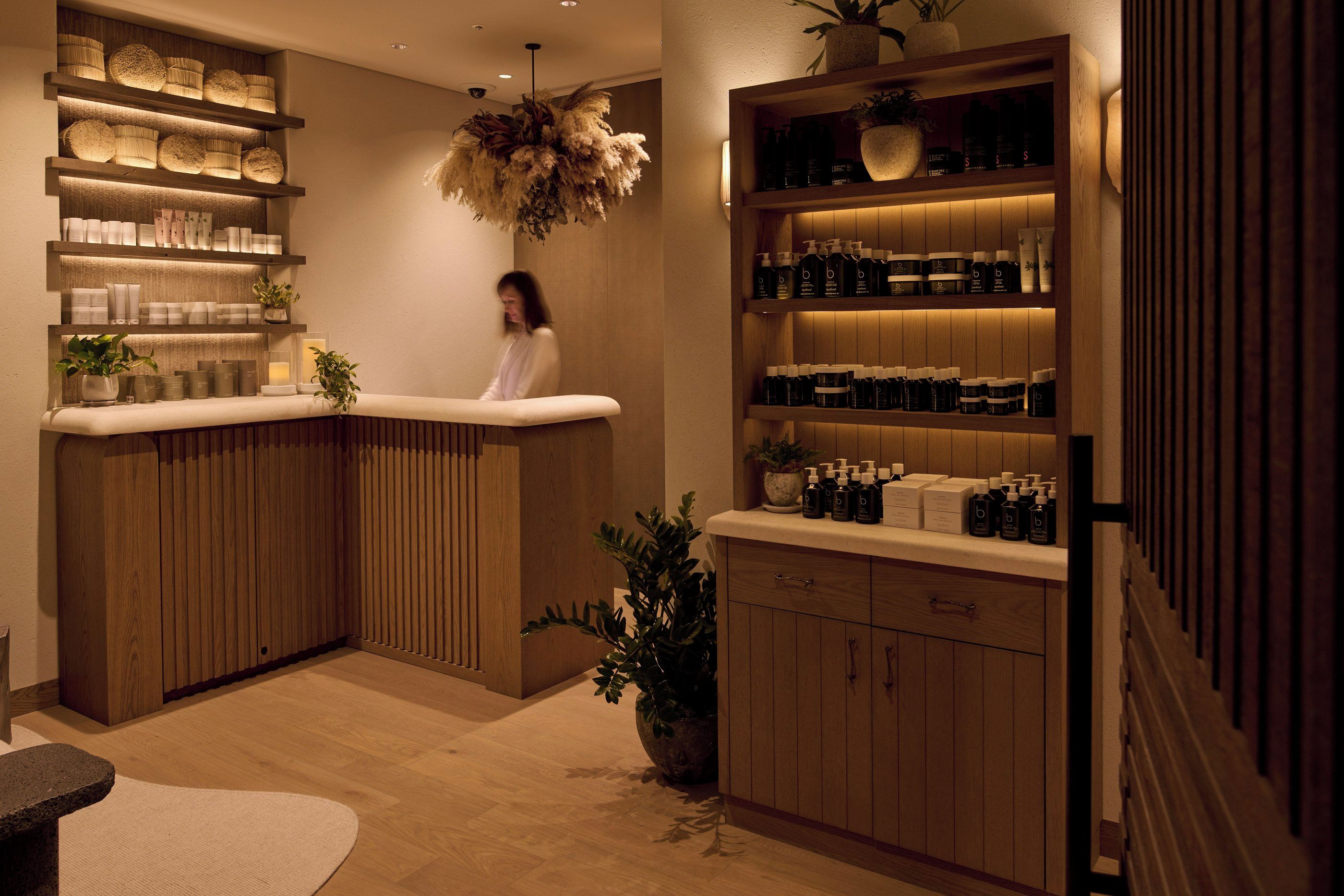 A spa-like setting with wooden paneling, shelves with products, and a person seated.