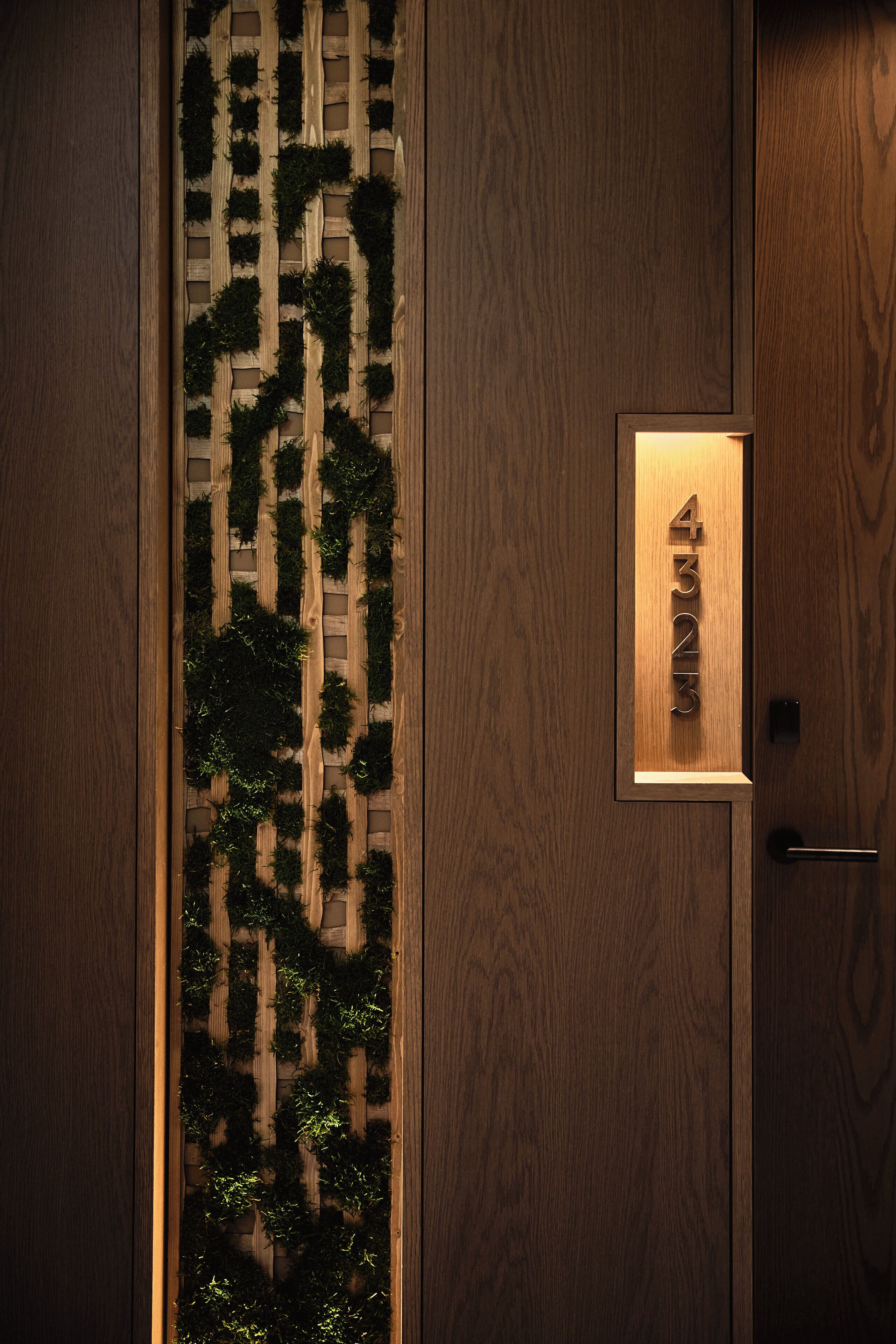 A wooden door with a vertical garden and a nameplate.