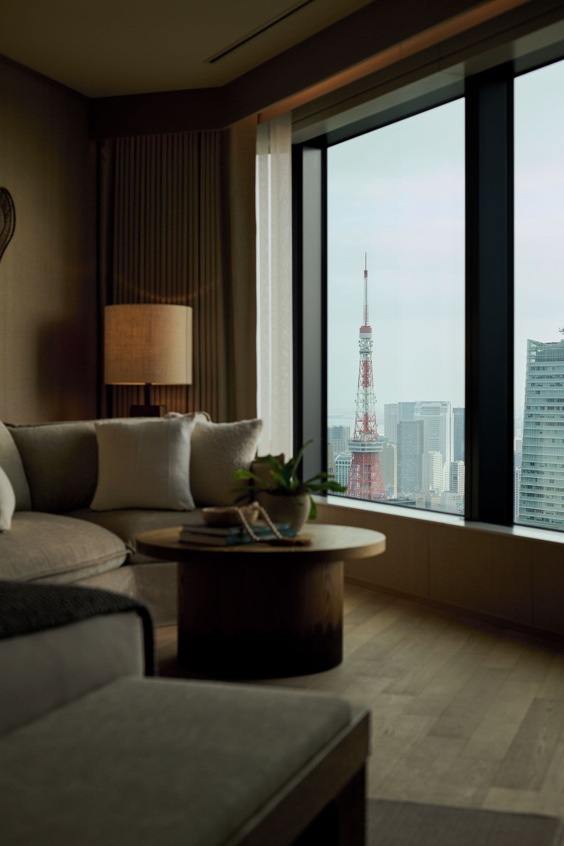 Ein modernes Hotelzimmer mit großem Fenster und Blick auf eine Stadtlandschaft sowie einem markanten Turm.
