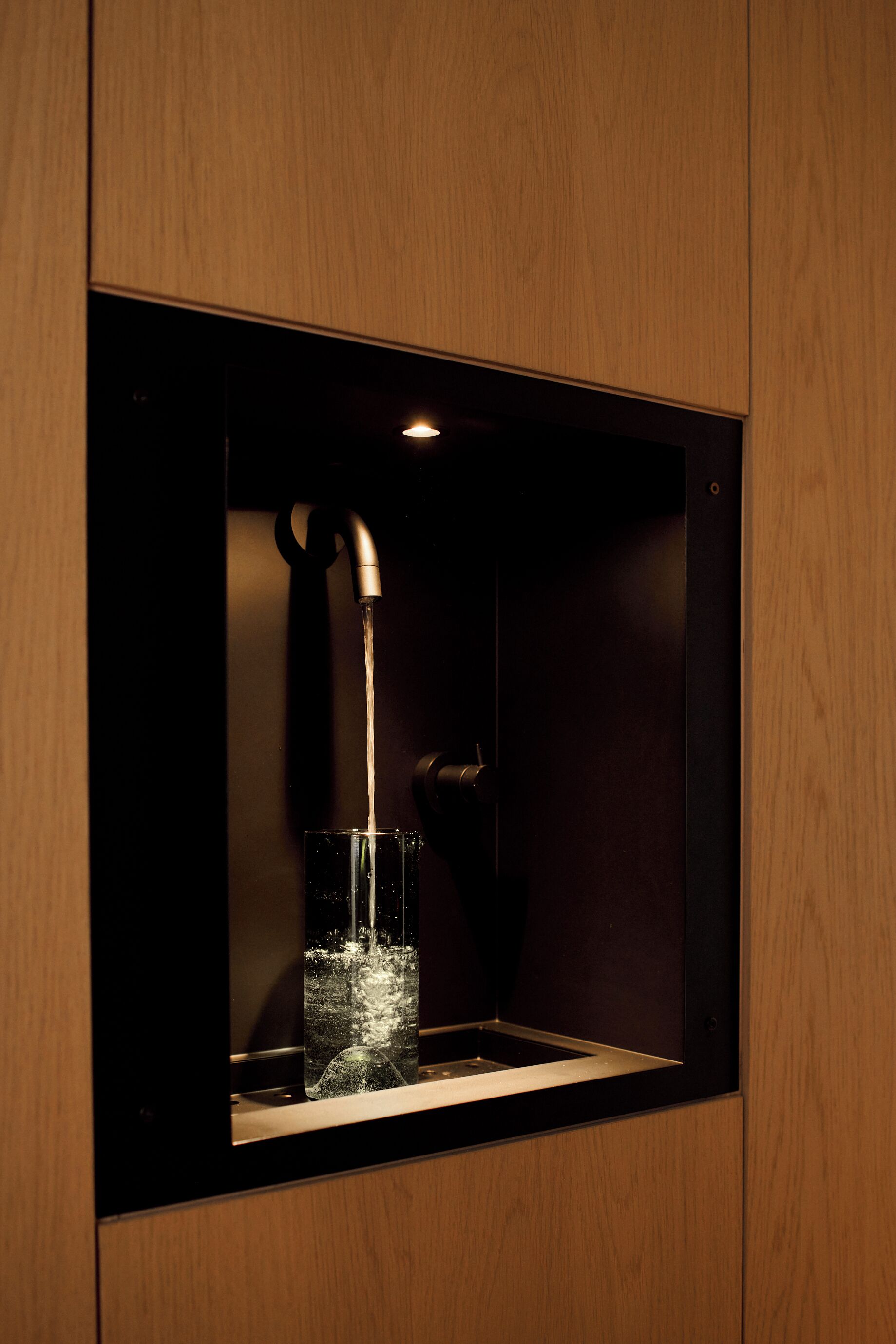 A modern bathroom with a built-in sink, a faucet, and a glass of water.