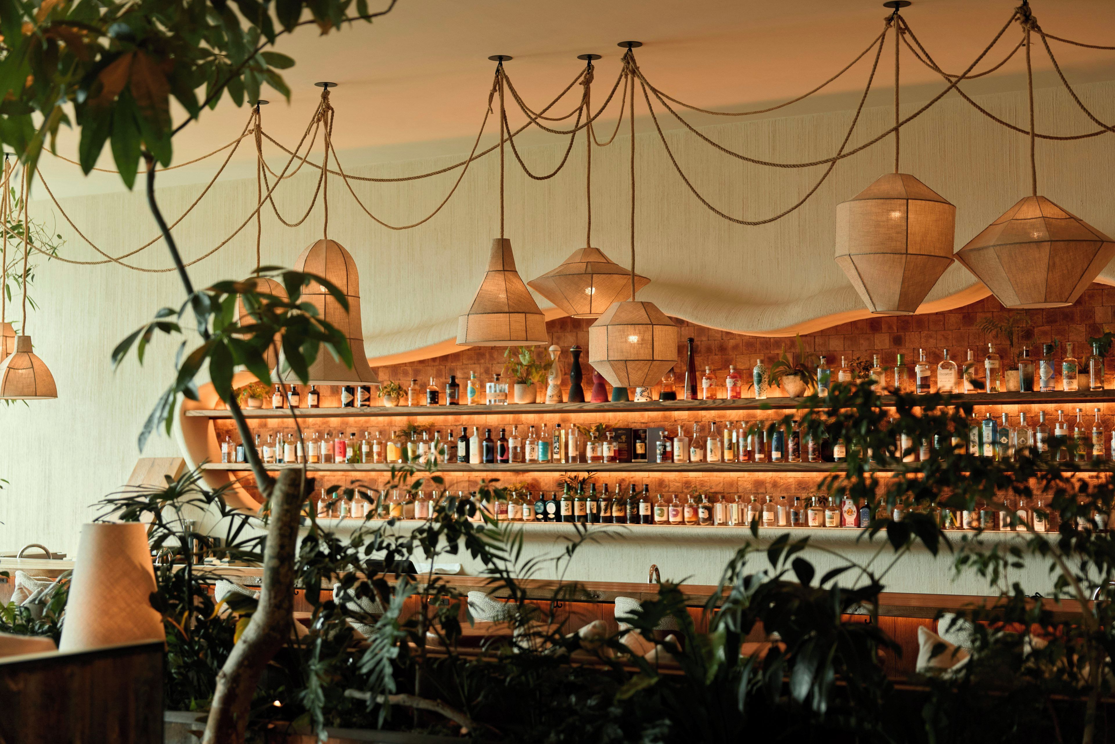 A bar area with multiple hanging pendant lights and shelves stocked with bottles.