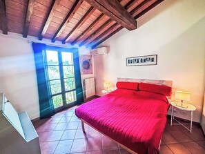 Une chambre avec un grand lit, une fenêtre, un radiateur et une petite table de chevet.