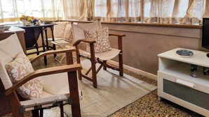 A cozy living room with wooden furniture, a television, and a window with curtains. - View of 2 historic towers • Lucca • 2 guests (Lucca)