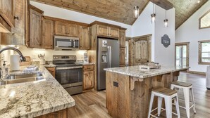 A kitchen with wooden cabinets, stainless steel appliances, a marble countertop, and a wooden ceiling. - Mountaintown Chalet | Ellijay, GA (Ellijay)