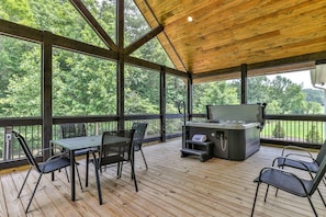 Ein überdachter Außenbereich mit Holzdeck, Grillstation und Tisch mit Stühlen.