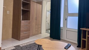 A room with a wooden wardrobe, a round wooden table, a remote control, and a door with frosted glass panels. - Apartment Centar (Ploce)