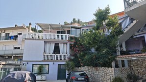 A residential building with a two-story balcony, a stone wall, and a parked car. - Apartment Centar (Ploce)