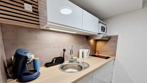 Una cocina moderna con un lavamanos integrado, una cafetera y un microondas.