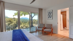 A bedroom with a large bed, two armchairs, a ceiling fan, and a view of the outdoors. - 4-bedroom house in Oakhurst with views, game room, hot tub, EV charger (Oakhurst)