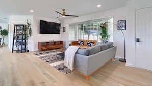A modern living room with a grey sofa, wooden floor, and a ceiling fan. - 4-bedroom house in Oakhurst with views, game room, hot tub, EV charger (Oakhurst)
