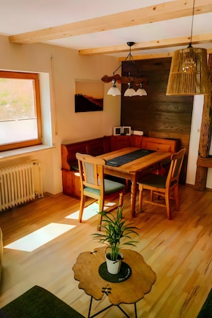 A wooden dining table with chairs, a bench, a potted plant, and a hanging light fixture.