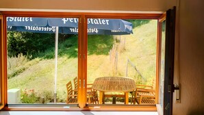 A room with a large window, a radiator, and a table with chairs. - Bästenbach Apartment: Idyllic Quiet Location with Mountain Views, Private Terrace & Wi-Fi (Bad Peterstal-Griesbach)
