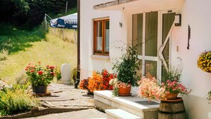 A white building with a number 18 sign, a small porch with steps, and potted plants. - Bästenbach Apartment: Idyllic Quiet Location with Mountain Views, Private Terrace & Wi-Fi (Bad Peterstal-Griesbach)