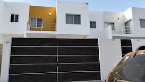 Um edifício residencial moderno de vários andares, com uma grande porta de garagem, uma varanda e uma pequena janela.