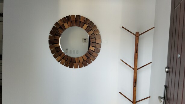 Decoração de parede circular de madeira com um porta-roupas de madeira ao lado.