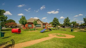 A playground with a red barrel, blue slide, and green benches. - Addison 2BR with 2 Pools + Gym Near Downtown Dallas (Addison)