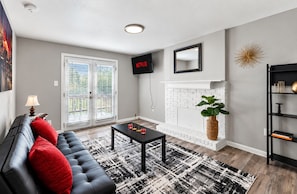 A living room with a black leather sofa, a coffee table, a fireplace, and a bookshelf.