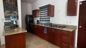 A modern kitchen with a central island, dark wooden cabinets, and a tiled floor. - Tacho's family hause, 5-star safe (La Paz)