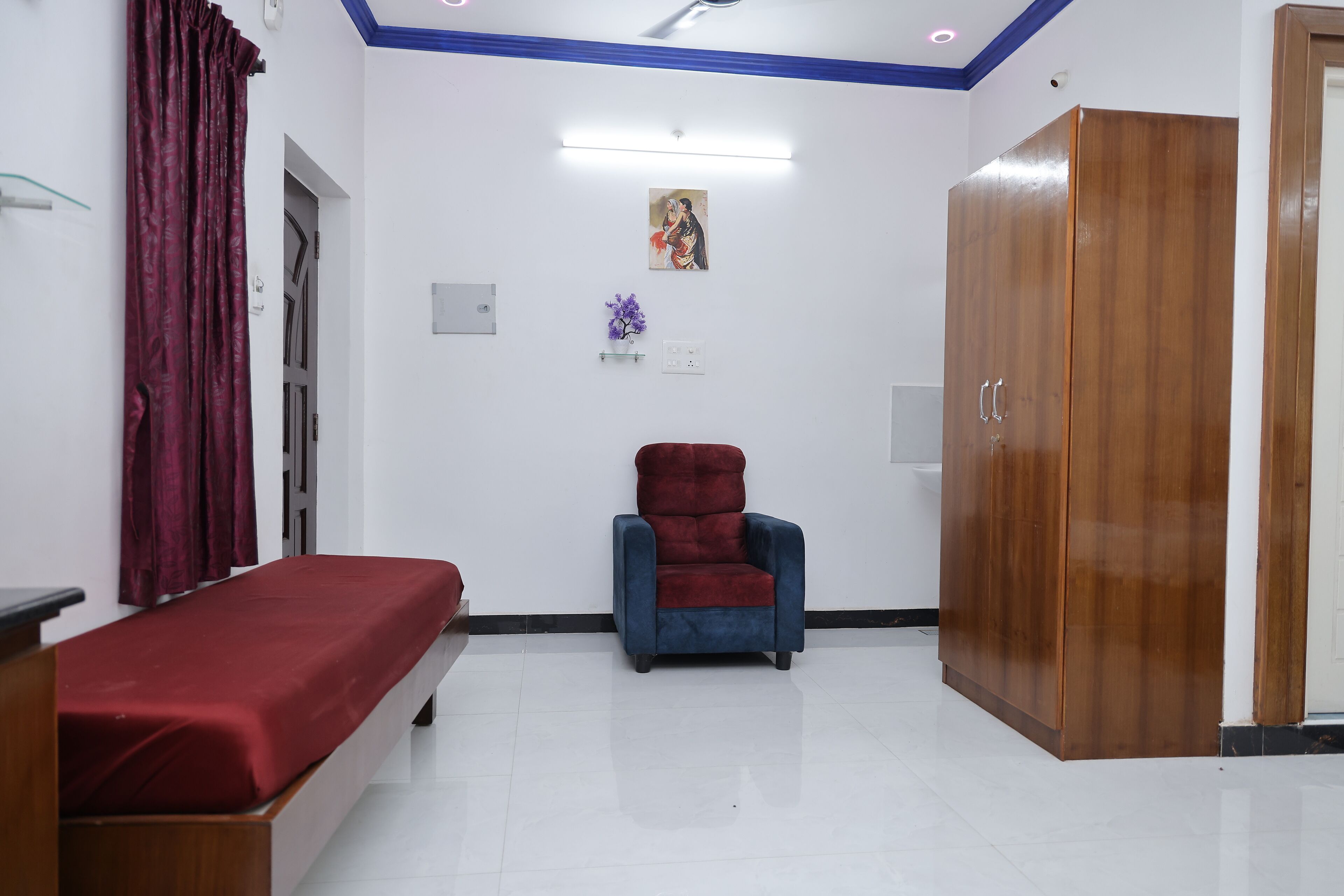 A room with a bed, a chair, a wardrobe, and a wall-mounted picture.