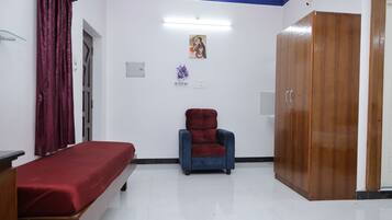 A room with a bed, a chair, a wardrobe, and a wall-mounted picture.