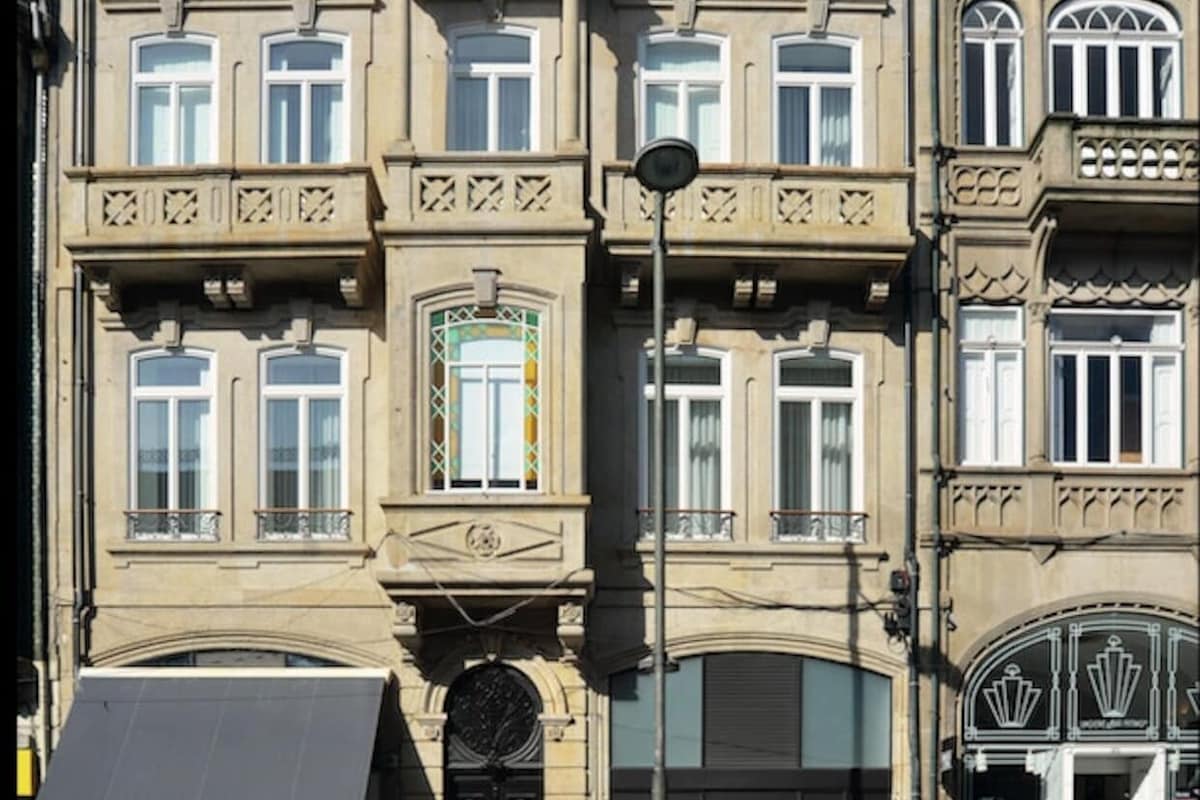 Un edificio de varios pisos con un estilo arquitectónico clásico, que presenta balcones ornamentados, ventanas amplias y una entrada central con un arco decorativo.