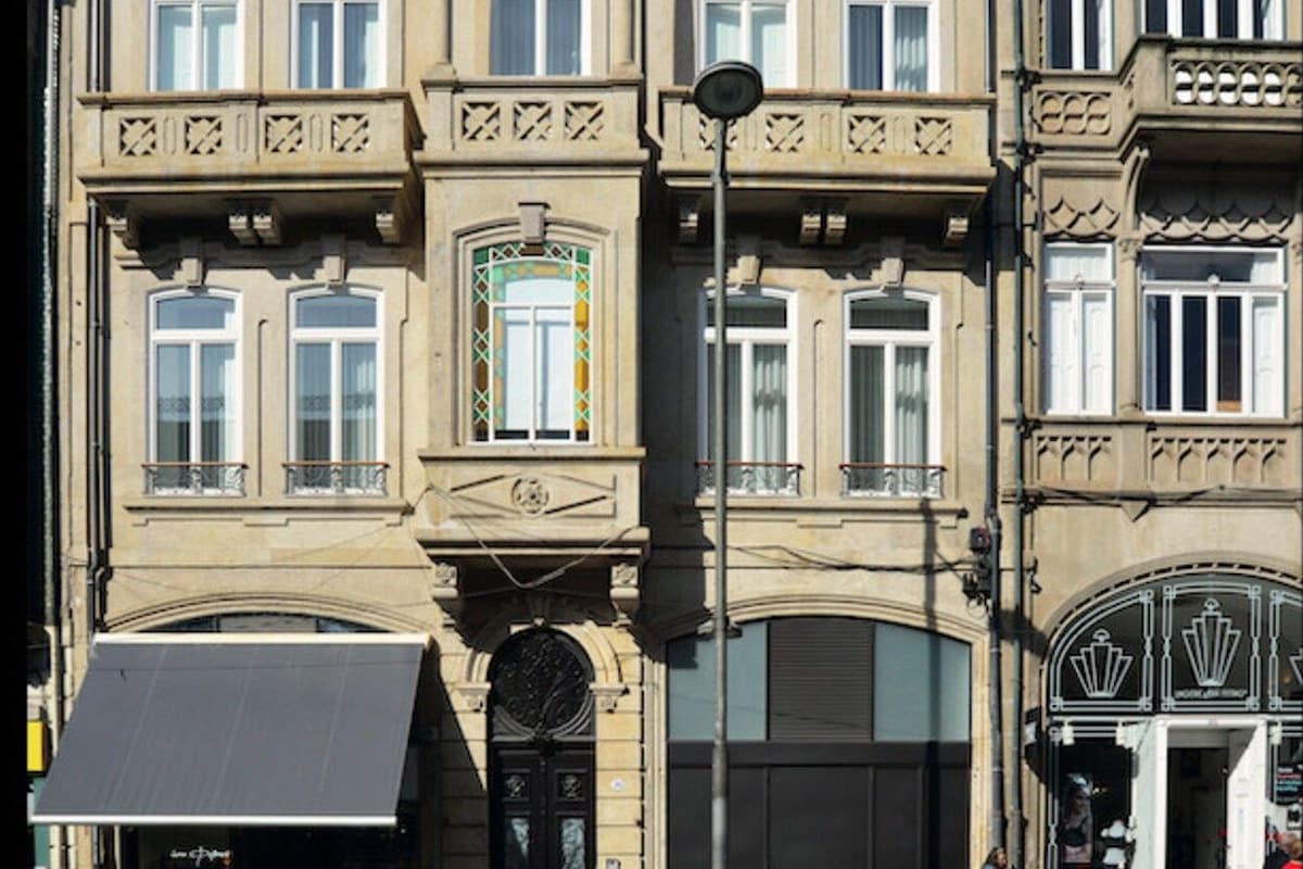 Un edificio de varios pisos con detalles arquitectónicos ornamentales, incluyendo balcones y ventanas decorativas.