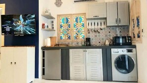 A compact kitchen with a washing machine, a microwave, and a TV. - Welcome to Dar Jaafar! Cozy Arabesque Style Holiday House in la Marsa Tunisie (La Marsa)