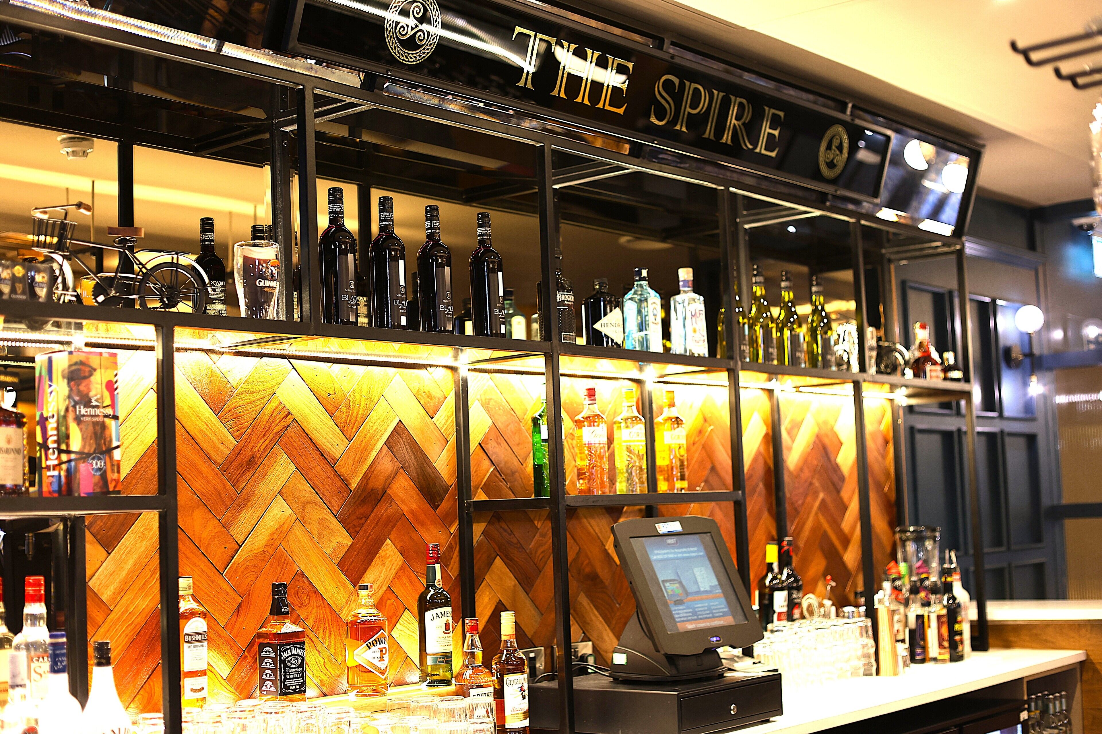 A bar with a herringbone wood panel wall and a cash register.