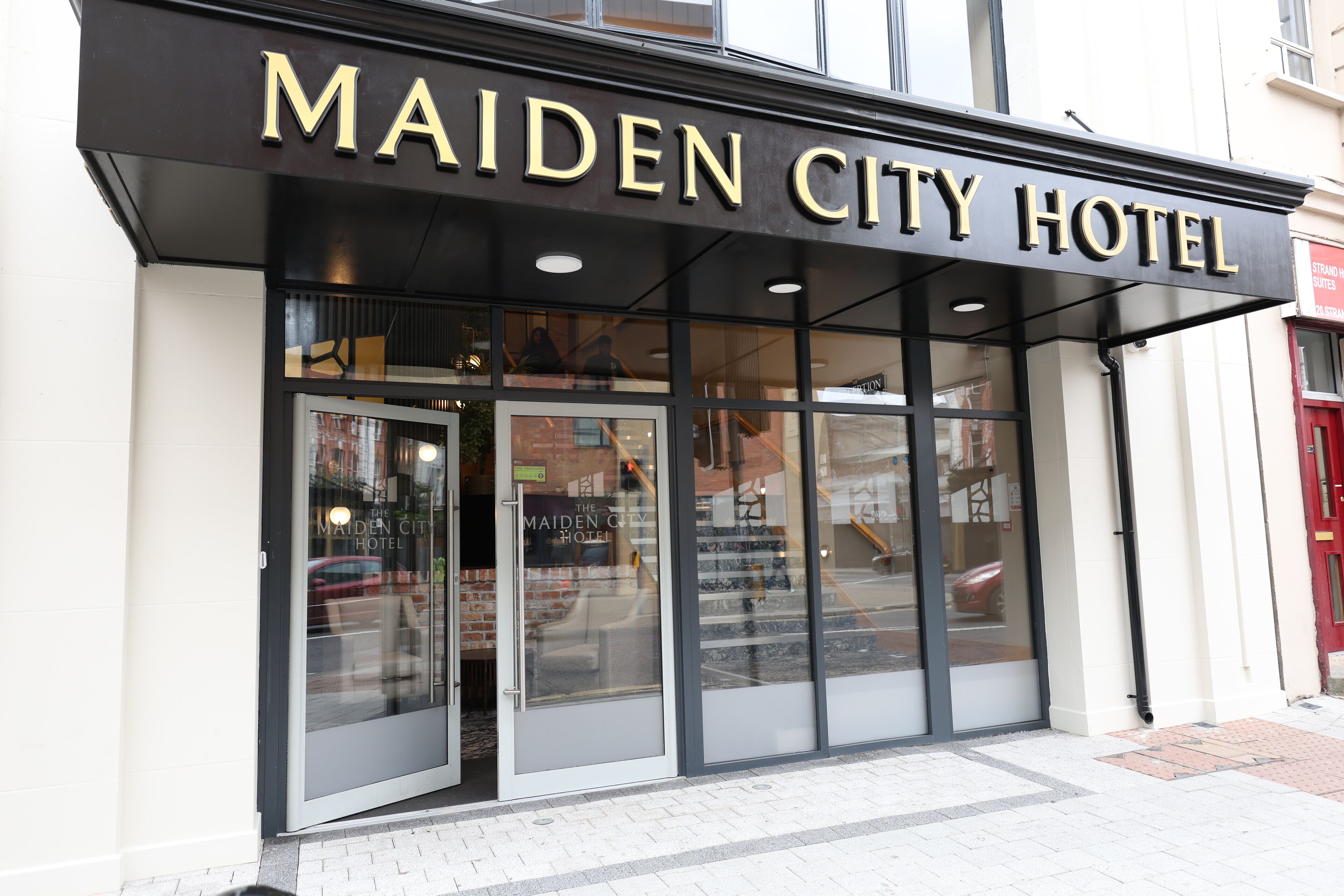 La façade de l’hôtel Maiden City, avec une enseigne bien visible au-dessus de l’entrée.