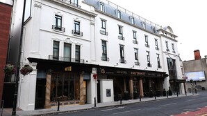 A white building with multiple windows and balconies, featuring signs for 'The Trinity Bar & Grill' and 'The City Hotel'. - The Maiden City Hotel (Londonderry)