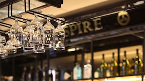 A bar area with a wooden herringbone wall, a cash register, and a variety of liquor bottles. - The Maiden City Hotel (Londonderry)