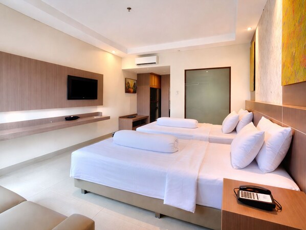 A modern hotel room with a large bed, a flat-screen TV, a bedside table with a phone, and a painting on the wall.