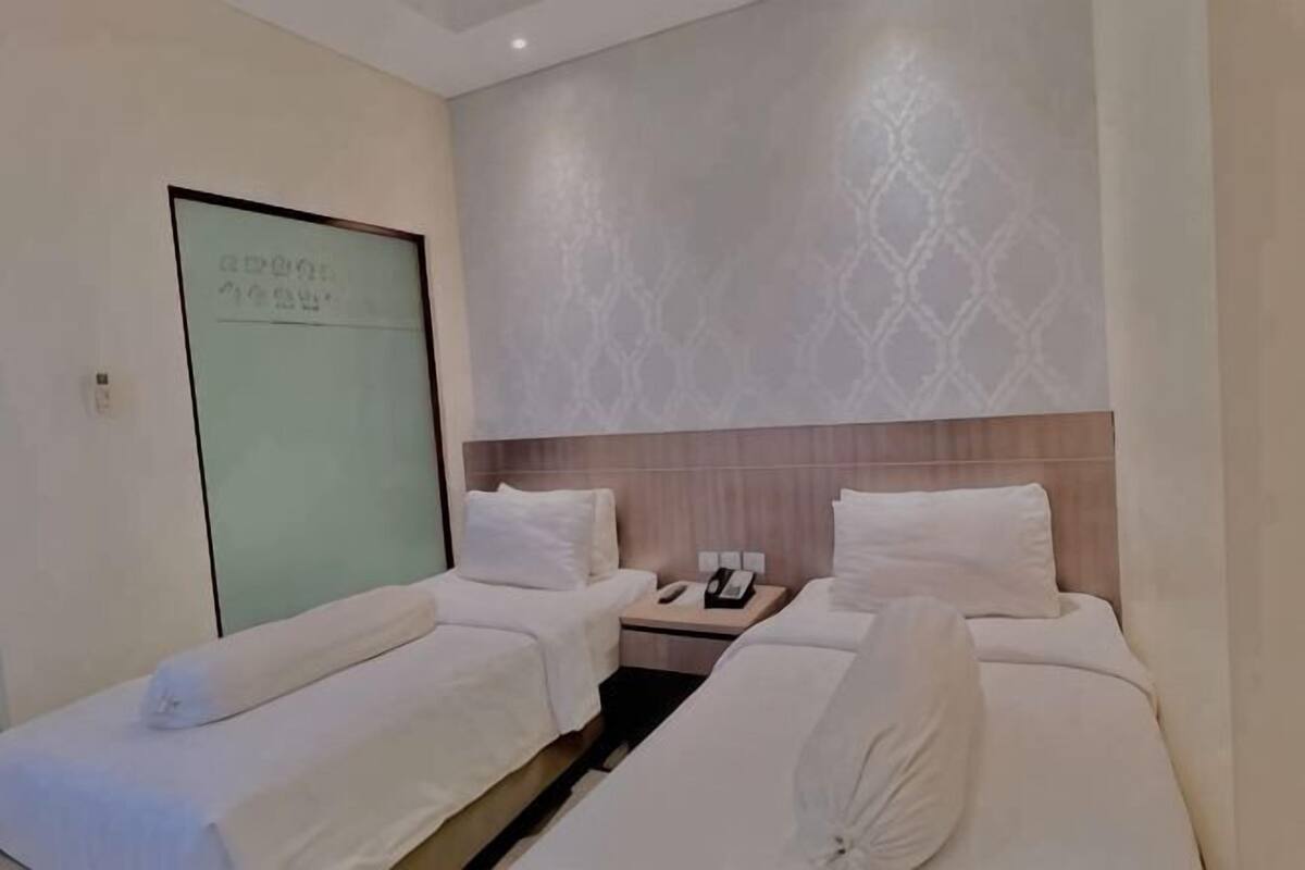 A hotel room with two beds, a nightstand, and a wall with a geometric pattern.