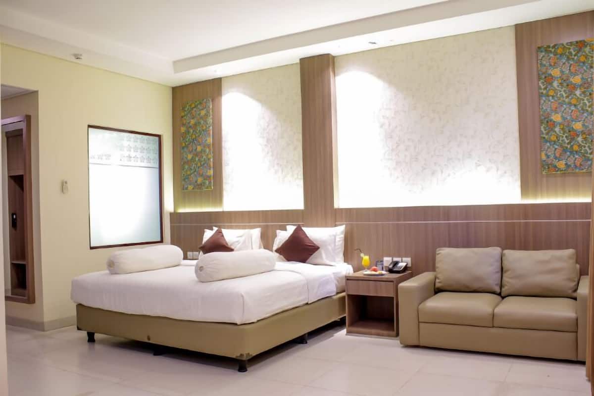 A hotel room with a bed, bedside table, and a sofa.