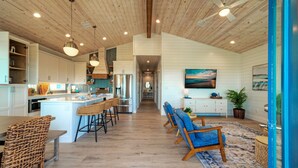 Una cocina amplia con una isla central, techo de madera e iluminación colgante.