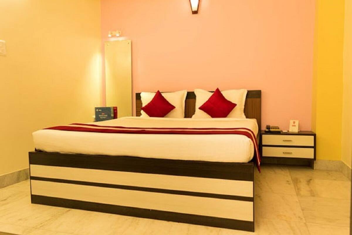 A neatly made bed with a striped headboard, a bedside table with a lamp, and a wall-mounted light fixture.