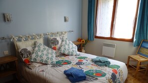 Un lit bien fait, avec une literie à motifs floraux, une table de chevet avec une lampe et une fenêtre avec des rideaux.