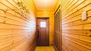 Un pasillo estrecho con paredes de madera, una puerta al final y un ventanal encima.