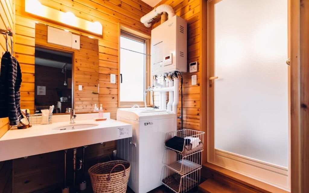 A wooden-paneled bathroom with a white sink, a mirror, and a white washing machine.