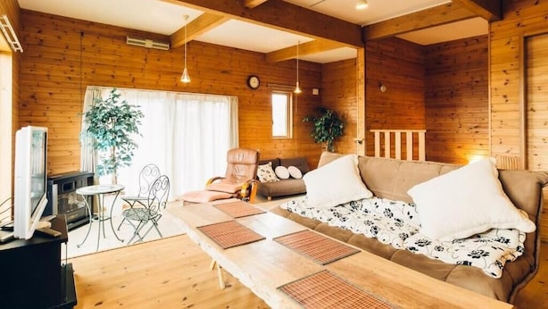 Un acogedor interior de cabaña con paredes de madera, un sofá, una mesa de comedor y un televisor.