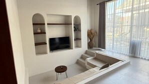 A modern living room with a built-in TV, built-in shelving, and a seating area. - Malasama suites hotel (Kuta)