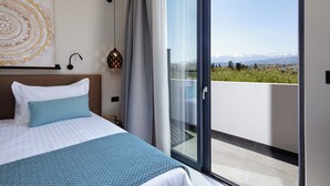 Een hotelkamer met een bed, een groot raam en uitzicht op bergen.
