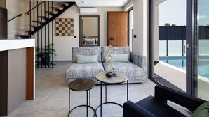 Een moderne woonkamer met een bank, salontafel en uitzicht op een zwembad.